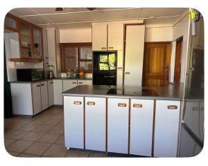 a kitchen with white cabinets and a black refrigerator at mission lifestyle in Empangeni
