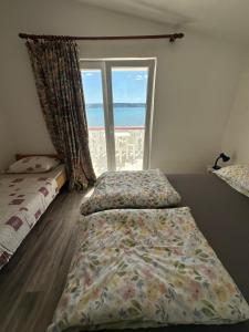 a bedroom with two beds and a large window at Apartment 2 (+1) in Ljubač