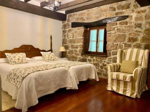 a bedroom with a bed and a stone wall at Posada la Punvieja in Los Tojos