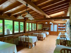 a dining room with tables and chairs and windows at Posada la Punvieja in Los Tojos