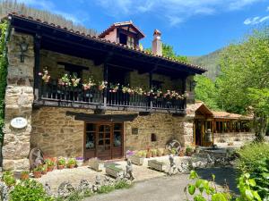 a stone house with a balcony with flowers on it at Posada la Punvieja in Los Tojos