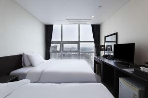 a hotel room with two beds and a desk and a window at Hotel K-Tree Pyeongtaek in Pyeongtaek +27 photos