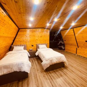 two beds in a room with wooden walls at اكواخ السوسنة السوداء in Ajloun