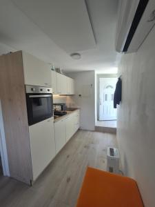 a kitchen with white cabinets and an orange table at Garsonjera Alina in Zgornje Gameljne