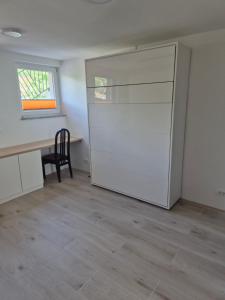 an empty room with a white refrigerator and a desk at Garsonjera Alina in Zgornje Gameljne
