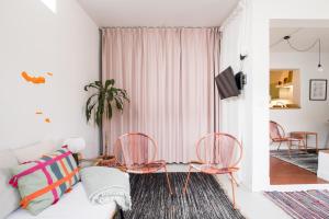 a living room with a white couch and pink chairs at 4BR, Garden & BBQ, 5min to Milícias Beach, Easy Park, Casa Yucca in São Roque