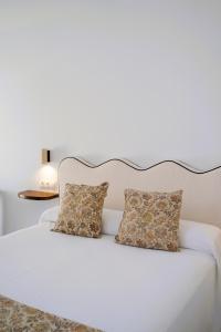 a white bed with two pillows on top of it at La joya de la Alcazaba in Jerez de los Caballeros