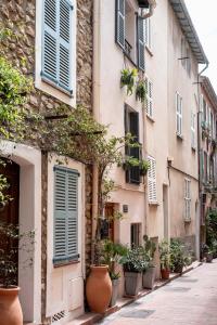 an old building with blue shuttered windows and potted plants at Maison entière à 100m de la mer in Antibes