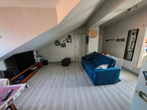 a living room with a blue couch and a tv at Attico Sole e Mare in Ventimiglia