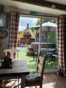 a dining room with a table and an umbrella at Bridie -rose rural shepherd hut , sleeps 4 with wood fuel hot tub -mini safari -on your doorstep small exotic animals in Kington