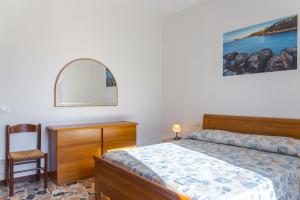a bedroom with a bed and a dresser and a chair at Passeggiata Alla Spiaggia in Campo nell'Elba +10 photos