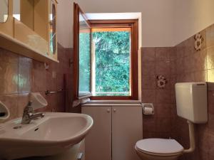un bagno con lavandino, WC e finestra di Appartamenti Alpi Graie - Cantoira a Cantoira