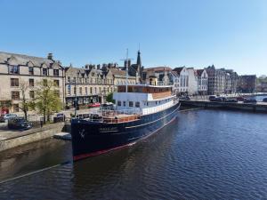 a boat is docked in a river in a city at Ocean Mist Leith in Edinburgh