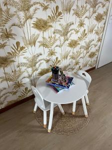 a white table and two white chairs in front of a wall at Le pré des noisettes in Angomont