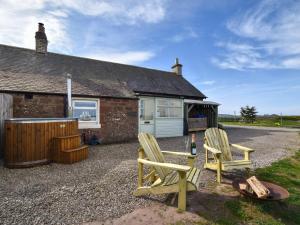 a cottage with two chairs and a table and a building at 2 Bed in Arbroath oc-90316 in Inverkeilor