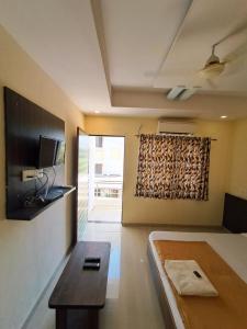 a room with a bed and a table and a television at Hotel Sai Neelam in Shirdi