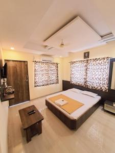 a bedroom with a large bed and a table at Hotel Sai Neelam in Shirdi