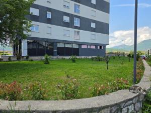 a building with a grass field in front of it at Lux Apartman Gostivar in Gostivar