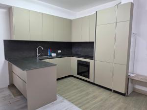 a kitchen with white cabinets and a black counter top at Lux Apartman Gostivar in Gostivar