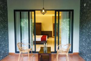 a room with two chairs and a table and a bed at Athirapilly Fernvalley Resort in Athirappilly