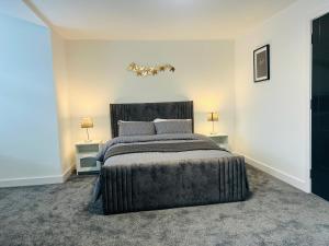 a bedroom with a large bed with two tables at Luxurious New Home Near Airport in Wythenshawe