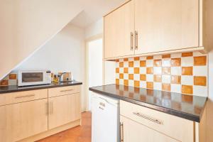 a kitchen with white cabinets and a microwave at Host & Stay - The Beach in Filey
