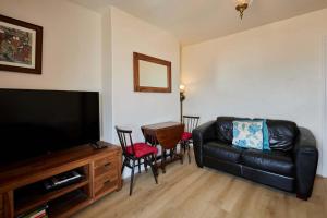 a living room with a black leather couch and a television at Host & Stay - The Beach in Filey