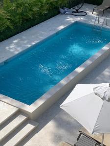 a swimming pool with a table and an umbrella at Xonadu con dominio in Puerto Plata