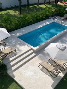 a swimming pool with two chairs and two umbrellas at Xonadu con dominio in Puerto Plata