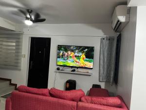 a living room with a red couch and a flat screen tv at Travellers Staycation in San Jose del Monte