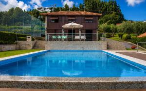 a house with a blue swimming pool in front of a house at Quinta da Eira do Sol in Guimarães +38 photos