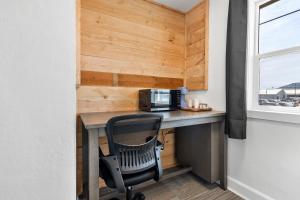 a desk with a microwave and a chair in a room at Copper Hill Suites in Butte +3 photos