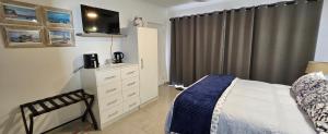 a bedroom with a bed and a dresser at Sonrisa on Point in Stompneusbaai +8 photos