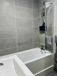 a bathroom with a white tub and a shower at Luxurious New Home Near Airport in Wythenshawe