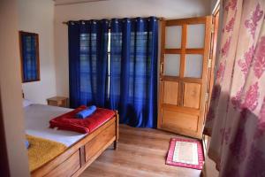 a bedroom with a bed and a window with blue curtains at Hillwoods homestay in Somvārpet +7 photos