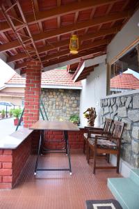 a patio with a table and chairs and a stone wall at Hillwoods homestay in Somvārpet
