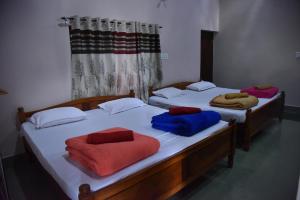 two beds with colorful pillows on them in a room at Hillwoods homestay in Somvārpet