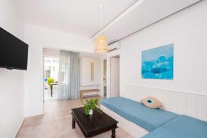 a white room with a blue bed and a table at Elvita beach hotel in Lartos