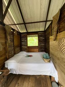 a bed in a wooden room with a window at Ancestra black ecolodge in Nuquí