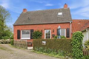 a red brick house with a hedge in front of it at Kiek In in Greetsiel