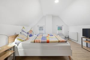 a white bedroom with a bed with pillows and a tv at Kiek In in Greetsiel