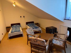 a room with two beds and a table and chairs at Fenyő Liget Vendégház in Balatonlelle