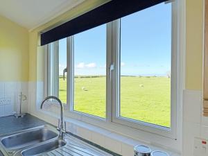 a kitchen sink with a window with a view of a field at Thelma's House - Uk48886 in Belford +19 photos