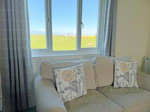 a white couch with pillows sitting in front of two windows at Thelma's House - Uk48886 in Belford