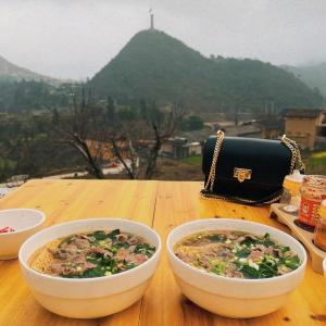 two bowls of food on a wooden table with a purse at Vị Lư homestay in Dồng Văn +40 photos