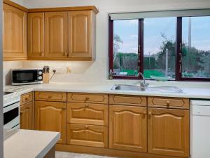 a kitchen with wooden cabinets and a sink and a window at The Martin's - Uk48870 in Belford