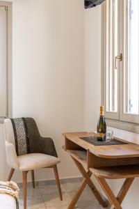 a dining room table with a chair and a bottle of wine at Iliovasilema Studios in Mytakas