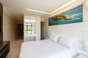 a bedroom with a white bed and a painting on the wall at Estudio232 - Asa Sul in Brasília