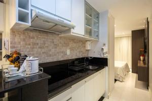 a kitchen with white cabinets and a black counter top at Estudio232 - Asa Sul in Brasília