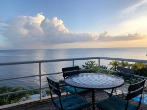 a balcony with a table and chairs and the ocean at Bleu Caraibe studio in Schœlcher